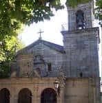 Primer plano de la fachada y campanario de la Iglesia de Santa Cristina de Lavadores entre la vegetación
