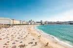 Playa de Orzán con numerosos bañistas y el horizonte de la ciudad