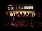 Escenario de un auditorio con músicos y pantalla del festival OUFF