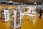 Interior de la biblioteca con mesas de lectura y estanterías