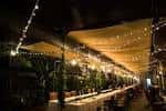 Ambiente nocturno de un evento con mesas y luces decorativas