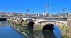 Puente de piedra sobre el río Lérez con edificios históricos al fondo