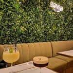 Área de asientos con pared de follaje verde y bebidas