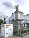 Estatua de los Hermanos García Naveira con panel informativo en la plaza