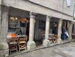 Fachada exterior del Bar Estrella con columnas de piedra y mesas en la calle