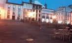 Vista exterior de Cafe Camalea al anochecer con mesas en la calle