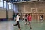Gimnasio universitario con cancha de baloncesto y estudiantes