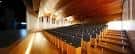 Interior del auditorio con filas de butacas y techo de madera