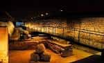 Sala de exposición arqueológica con restos antiguos y muros de piedra