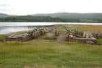 Restos arqueológicos del campamento romano con arco reconstruido y lago al fondo