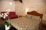 Habitación de hotel con cama, sofá rojo y orquídeas decorativas