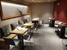 Área de comedor informal con mesas de madera y bancos tapizados