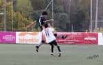 Jugadores de fútbol en acción con pancarta de Telemiño en el fondo