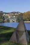 Escultura piramidal de piedra con el río y el puente al fondo