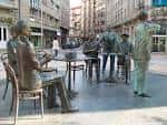 Primer plano angulado del monumento 'La Tertulia' con la calle de fondo