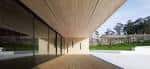 Detalle arquitectónico del exterior del Centro Social Casa Verde con voladizo de madera y ventanales