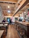 Interior rústico de O Parvadas con barra y mesas de madera