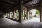 Pasillo abovedado del claustro con arcos de piedra y techo de madera