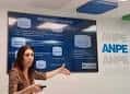 Sala de eventos con presentadora y logo de ANPE en la pared