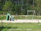 Zona de juegos infantiles con columpios y un área de césped en el Parque Forestal de Beade
