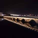 Puente del Burgo iluminado por la noche con reflejos dorados en el río