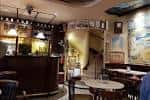 Interior del café mostrando la barra y una escalera de caracol