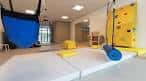 Sala de terapia ocupacional con colchonetas y pared de escalada
