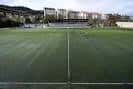 Campo de fútbol de Os Carrís desde el césped, mostrando las gradas y edificios circundantes.
