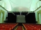 Auditorio con butacas rojas y escenario preparado para eventos