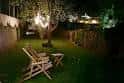 Jardín exterior iluminado por la noche con zona de descanso
