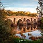 Puente romano al atardecer con el río Miño y la ciudad de Lugo de fondo