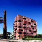 Vista exterior de edificio moderno con fachada de ladrillo y chimenea industrial