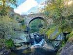 Puente medieval sobre el río Almofrei con cascadas y vegetación