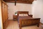 Habitación de hotel con cama de madera y vigas de madera en el techo