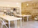 Interior de un espacio de coworking con mesas blancas y pared de piedra vista