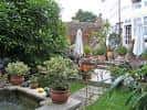 Jardín amurallado con sombrillas y mobiliario exterior