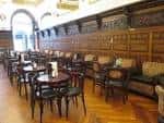 Disposición de mesas y sillas a lo largo del salón con paneles de madera