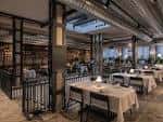 Zona de comedor con mesas vestidas y ambiente moderno