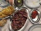 Plato de carne a la parrilla con patatas fritas y guarniciones en mesa de restaurante