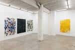 Amplia sala de exposición de la galería con obras de arte y pilar