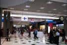 Pasillo concurrido del centro comercial con entrada a tiendas y restaurantes