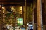 Interior rústico de un salón de eventos o restaurante con mesas puestas y pared de piedra