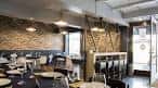 Salón interior de un restaurante moderno con paredes de piedra y mesas preparadas en Vigo