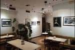Sala interior luminosa con mesas, bancos y exposición de arte en las paredes