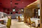 Amplio salón comedor con mesas vestidas y decoración moderna en tonos rojos