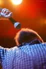 Cantante con micrófono en el escenario bajo luces cálidas