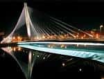 Puente de los Tirantes iluminado de noche con reflejo en el río