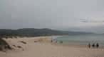 Playa de Doniños con bañistas y cielo nublado