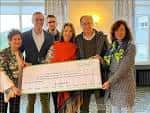Grupo de personas posando con un cheque de donación en un evento de la AECC.