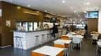 Interior de una cafetería luminosa con barra de azulejos blancos en Vigo
